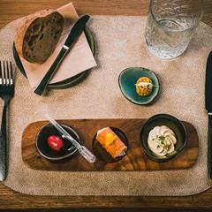 Elegant starter with bread, cream, cannolo, and dips on a carefully set dining table.
