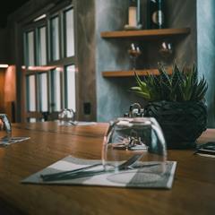 Close-up of a set wooden table with glasses, cutlery, and succulents