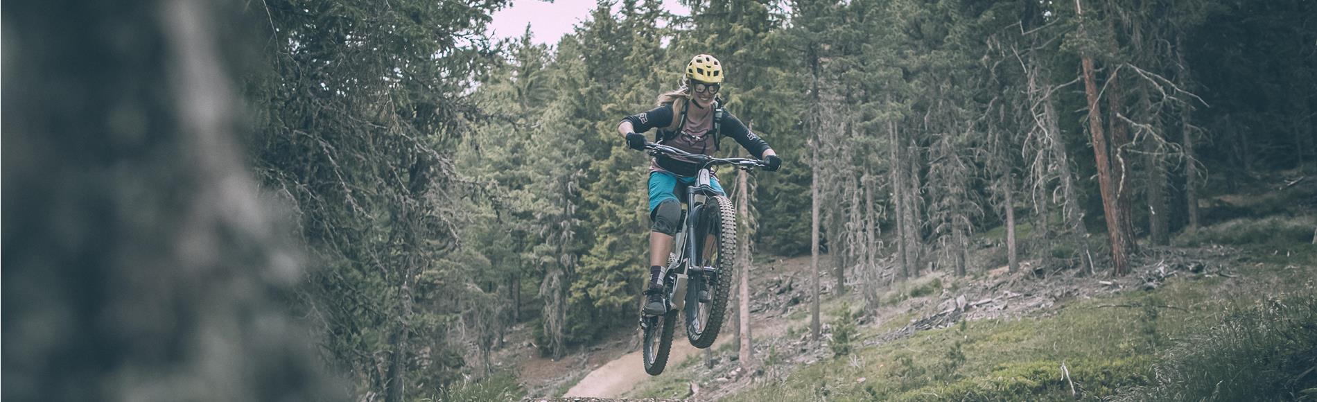 Ciclista salta con la bici su un sentiero nel bosco.