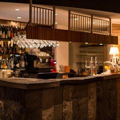Our elegant bar with stone paneling, glasses, bottles, and warm ambient lighting.