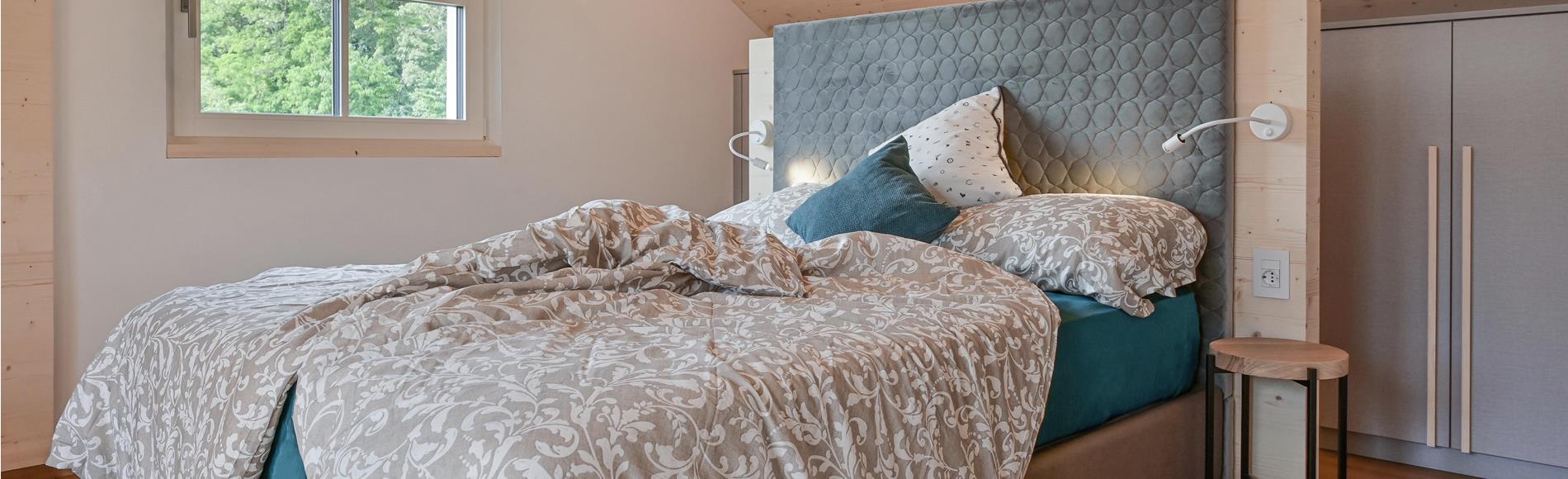 The bedroom with a double bed in the apartment with balcony