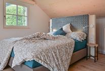 The bedroom with a double bed in the apartment with balcony